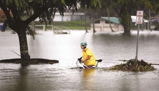 A woman pushes her bicycle through flooding caused by Hurricane Lane in Hilo, Hawaii.
