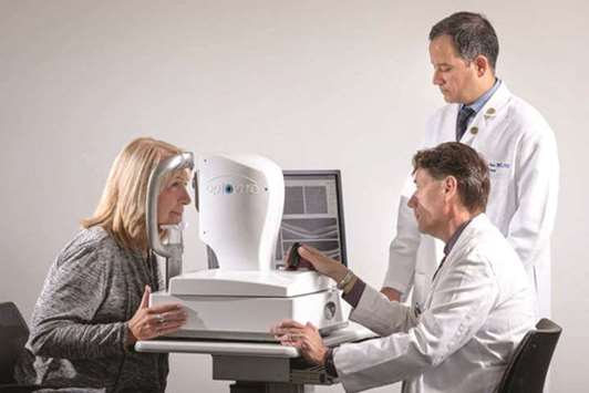 Dr Gregory Van Stavern (seated) and Dr Rajendra Apte examine the eyes of a woman using technology that one day may make it possible to screen patients for Alzheimeru2019s disease years before symptoms begin.