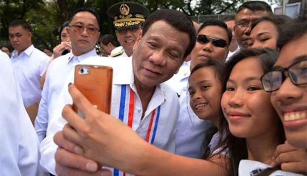 Philippines' President Rodrigo Duterte poses for a selfie with students after a wreath-laying ceremony to commemorate the National Heroes' Day at the Heroes Cemetery in Manila on Monday.