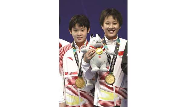 Gold medallists Zhang Minjie and Zhang Jiaqi of China pose on the podium for the womenu2019s Synchronised 10m Platform diving event at the GBK Aquatics Center in Jakarta yesterday. (Reuters)