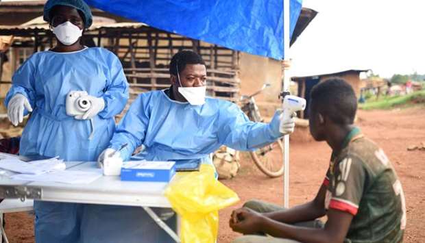 Congolese health workers take the temperature of a civilian before administering the Ebola vaccinati