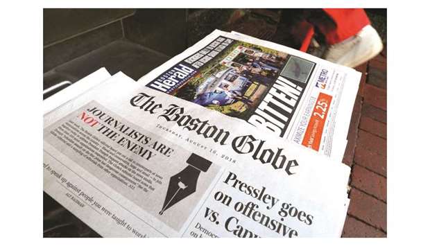 This picture taken on August 16 shows a man walking past the front page of the Boston Globe newspaper, referencing their  editorial defence of press freedom.