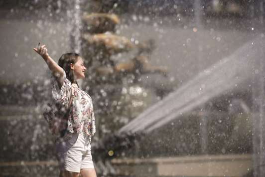 A woman cools off in a fountain during the summer heatwave in Paris.