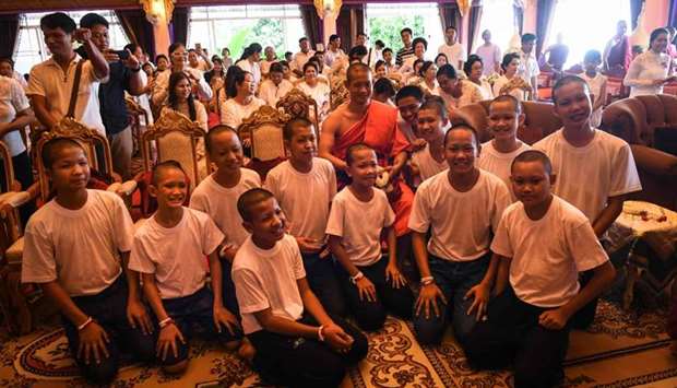 Thai coach Ekkapol Chantawong (C) and all 12 members of the ,Wild Boars, football team pose for a photo together after a ceremony to mark the end of the 11 players' retreat as novice Buddhist monks at the Wat Phra That Doi Tung temple in the Mae Sai district of Chiang Rai province on Saturday.