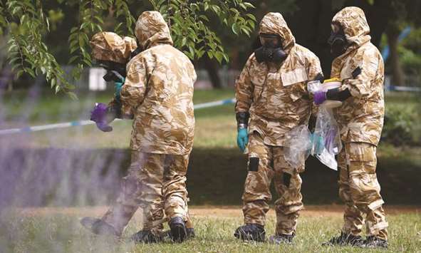 People in protective suits collect an item and photograph its location in Salisbury.