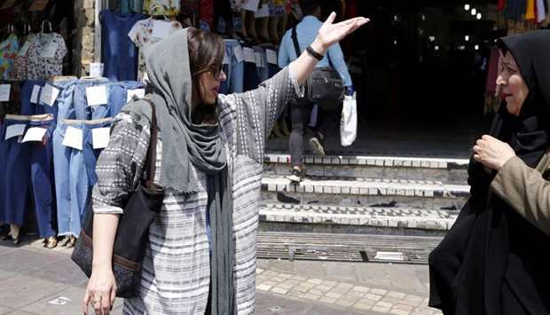 Two Iranian women talk on the street in a shopping district in central Tehran