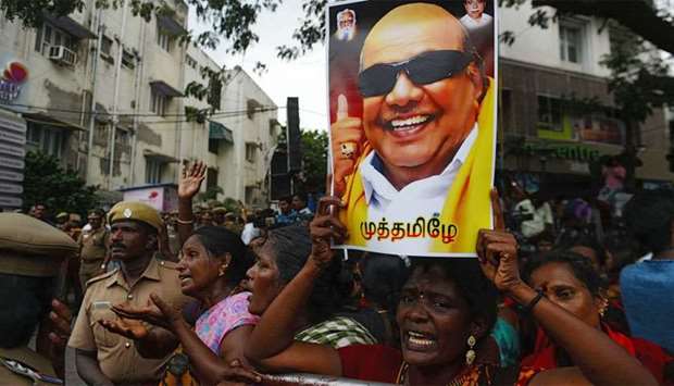 A supporter holds a portrait of M. Karunanidhi in front of the hospital in Chennai.