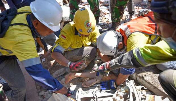 Rescue workers extract a woman, who survived after being trapped in rubble since Sunday's earthquake, in Tanjung, North Lombok, Indonesia.