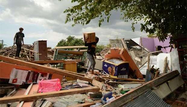 A young man salvages belongings as he climbs over debris of a collapsed house in Kayangan in northern Lombok island on Thursday.