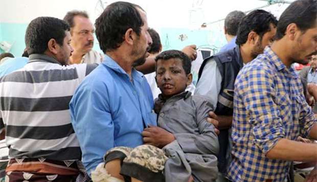 A Yemeni man holds a boy who was injured by an air strike in Saada on Thursday.