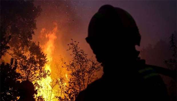Firefighters watch trees burning as they combat a wildfire close to Monchique in the Portuguese Algarve on Wednesday.