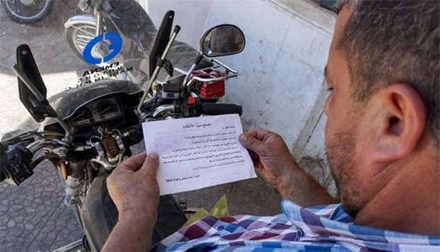 A Syrian man holds a leaflet stamped with the government forces' seal and dropped by helicopters flying over the northwestern Syrian town of Binnish on Thursday.