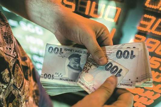 A money changer counts Turkish lira banknotes at a currency exchange office in Istanbul on Wednesday. The government has set a growth target of less than 4%, down from 5.5% originally, Treasury and Finance Minister Berat Albayraku2019s office said.