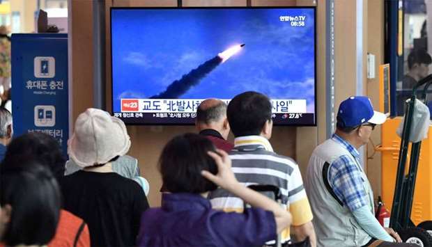 People watch a television news screen showing file footage of North Korea's missile launch, at a railway station