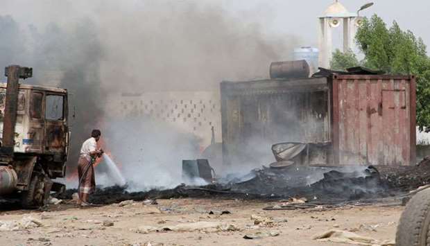 Man extinguishes fire at a car service shop during clashes in Aden