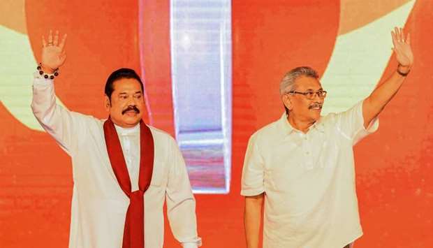 Sri Lanka's opposition leader and former president Mahinda Rajapakse (L) and his brother, Gotabhaya Rajapakse (R), wave to party supporters shortly after announcing the latter as the candidate for the newly formed party to contest this year's presidential elections in Colombo