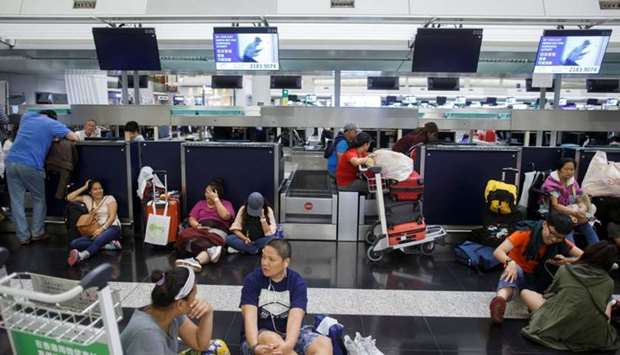 Passengers rest at the check-in counters after all flights were cancelled due to a protest inside the airport terminal in Hong Kong