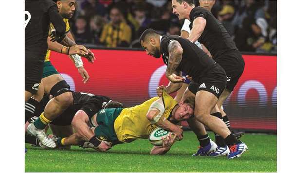 Australiau2019s captain Michael Hooper is tackled to the ground by New Zealandu2019s Dane Coles (right) and his teammates during their Rugby Championship Bledisloe Cup match in Perth on Saturday. (AFP)