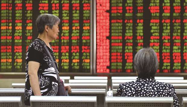 Women talk in front of a screen showing stock prices at a securities company in Beijing. Shanghaiu2019s bourse closed up 1.5% to 2,814.99 points yesterday.