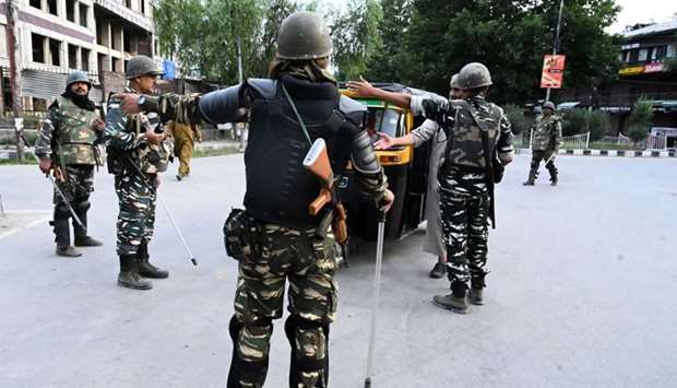 Security personnel stop an auto-rickshaw for questioning at a roadblock during a lockdown in Srinagar yesterday