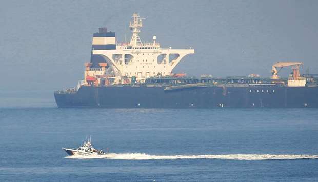 A Spanish Civil Guard boat sails past Iranian oil tanker Grace 1 as it sits anchored after it was seized in July by British Royal Marines off the coast of the British Mediterranean territory on suspicion of violating sanctions against Syria, in the Strait of Gibraltar, southern Spain yesterday.