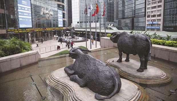 Sculptures of water buffaloes stand as pedestrians walk past an electronic ticker board and screens displaying stock figures outside the Exchange Square complex, which houses the Hong Kong Stock Exchange. The Hang Seng fell 2.1% to 25,281.30 points yesterday.