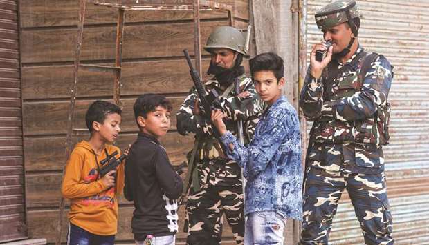 Children play with toy guns next to Indian security force personnel in Srinagar yesterday.