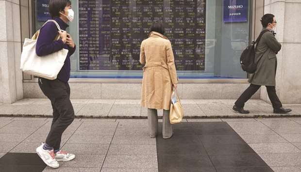 A pedestrian looks at an electronic stock board outside a securities firm in Tokyo. Japanese shares ended 1% higher at 20,655.13 points yesterday.