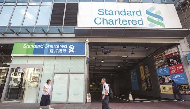 Pedestrians walk past a Standard Chartered bank branch in Hong Kong. The bank is targeting growing its private banking assets by 50% to about $100bn in three to five years and will hire dozens of bankers in Hong Kong and Singapore towards that goal, a senior executive of the lender said.