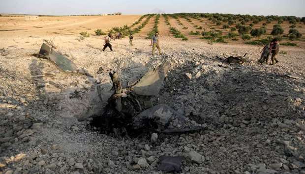 Rebel fighters gather near the remains of a downed warplane near the town of Khan Sheikhun in the south of Idlib province