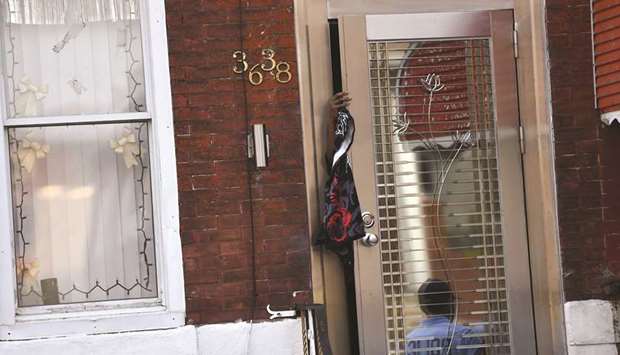 A resident reaches out from her front door as a police officer is reflected while responding to an u2018active shooteru2019 situation in Philadelphia.