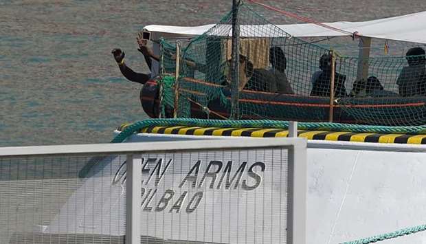 ) In this file photo taken on July 4, 2018 migrants stand on the deck of the Spanish NGO Proactiva Open Arms ship as it arrives at Barcelona's harbour, carrying 60 migrants rescued as they tried to cross the Mediterranean from Libya after Italy and Malta refused access.