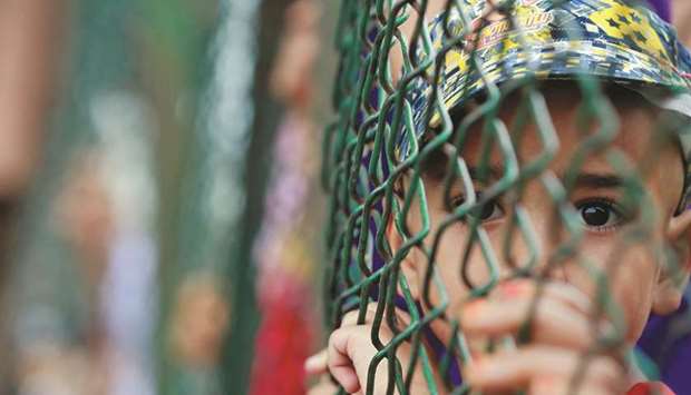 A Kashmiri child looks from behind a fence at a protest site after Friday prayers yesterday.