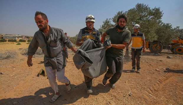 Members of the Syrian Civil Defense (White Helmets) carry away in a blanket a person rescued from the rubble of a collapsed building following a reported regime air strike on the village of Deir Sharqi on the eastern outskirts of Maaret al-Numan in Syria's northern province of Idlib
