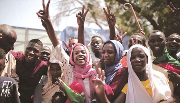 Sudanese men and women celebrate outside the Friendship Hall in the capital Khartoum where generals and protest leaders signed a historic transitional constitution meant to pave the way for civilian rule, yesterday.