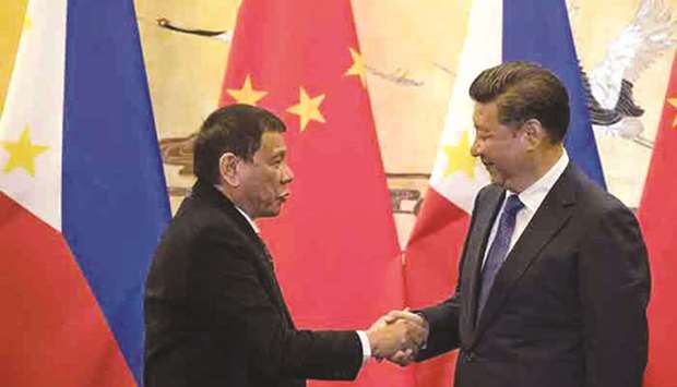 This photo taken on October 20, 2016 shows President Rodrigo Duterte and his Chinese counterpart Xi Jinping shaking hands after a signing ceremony in Beijing.