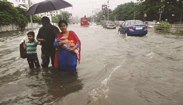 A family with a newborn wade through a flooded street following heavy rains in Kolkata yesterday.