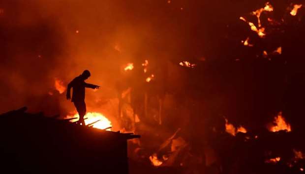 A Bangladeshi man tries to extinguish a fire as a fire blazes in a slum in Dhaka yesterday