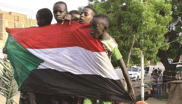 Young Sudanese boys carry a national flag as they celebrate in Bahri, the capital Khartoumu2019s northern district, a day after generals and protest leaders signed a historic transitional constitution meant to pave the way for civilian rule, yesterday.