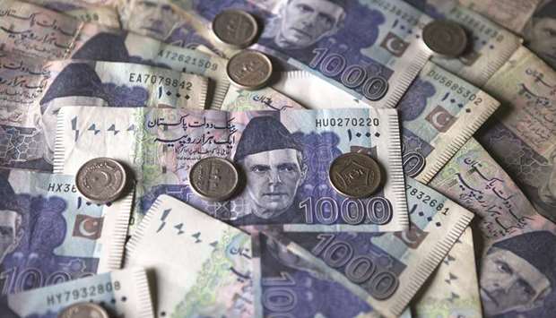 Pakistan rupee banknotes and coins in an arranged photograph.