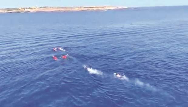 A still image taken from a video shows migrants attempting to swim ashore after jumping off the Spanish rescue ship Open Arms, off the coast of Lampedusa, Italy.