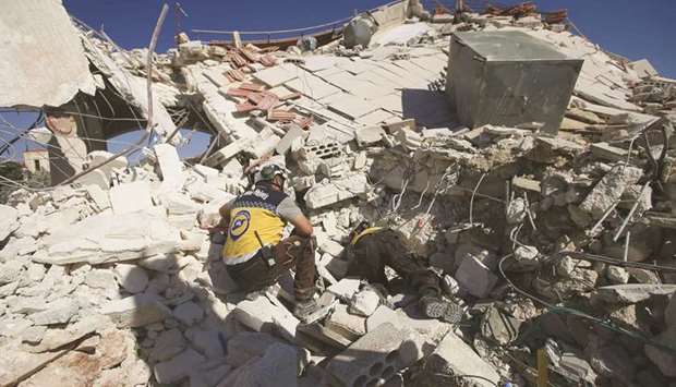 Members of the Syrian Civil Defence (White Helmets) look for bodies amidst the rubble following a reported government air strike in the village of Benin, about 30 kilometres south of Idlib in northwestern Syria, yesterday.