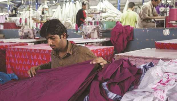  A worker inspects a piece of fabric ahead of stitching at a textile manufacturer in Karachi. 