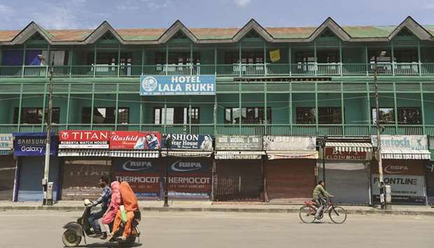 A family on a scooter rides past an empty hotel in the Lal Chowk area of Srinagar yesterday.