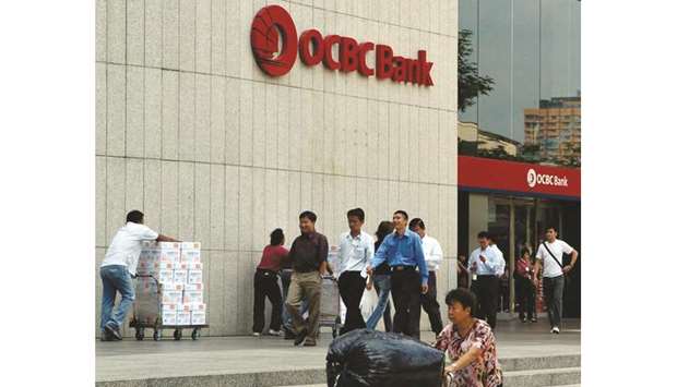 Pedestrians walk past the Oversea-Chinese Banking Corp headquarters in the central business district of Singapore. The bank would take a minority stake in any virtual-banking joint venture and sees it as a way to tap new customers and markets, sources said yesterday.