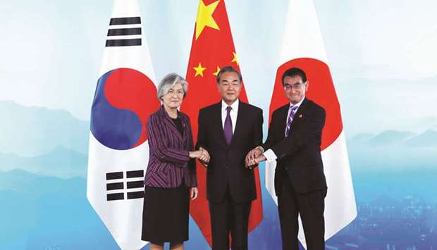 Chinese Foreign Minister Wang Yi (centre), South Korean Foreign Minister Kang Kyung-wha (left) and Japanese Foreign Minister Taro Kono shake hands ahead the ninth trilateral foreign ministersu2019 meeting among China, South Korea and Japan at Gubei Town in Beijing yesterday.