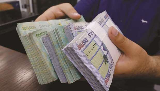 A money exchange vendor displays Lebanese pound banknotes at his shop in Beirut (file). Fitch downgraded Lebanon for the first time in three years, taking the sovereign down two notches to CCC, according to a statement on Friday.