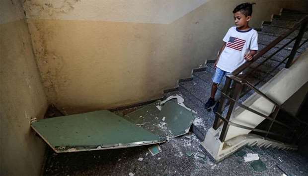 A boy walks past debris in a building housing a media centre of the Lebanese group Hezbollah that was damaged after two drones came down in its earlier in the day
