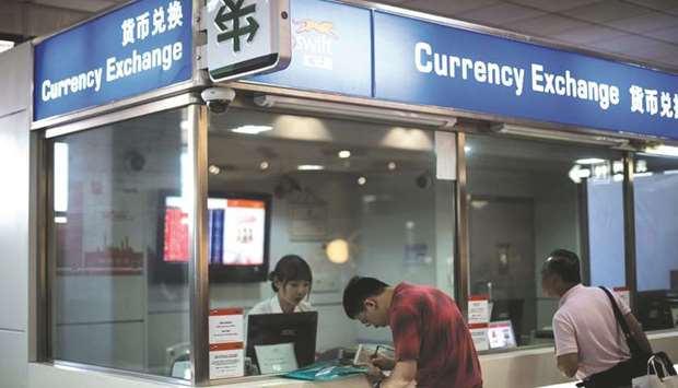 A man changes foreign currency into Chinese yuan at an exchange office in Hongqiao airport in Shanghai (file). The yuan has tumbled 1% over the past seven sessions, the worst performance in Asia, as uncertainty over the trade dispute with the US lingers.