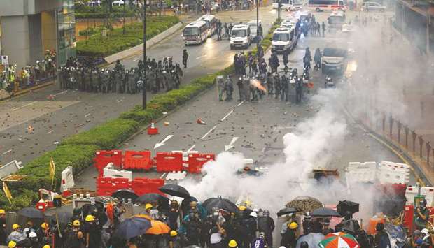 Riot police shooting a teargas canister as demonstrators take cover behind barricades during a protest in Tsuen Wan, Hong Kong, yesterday.